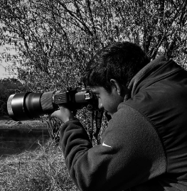 black and white photo of Fareed taking a photograph in some trees